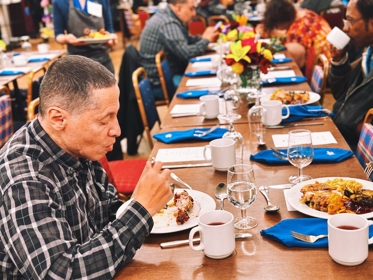 A man in the foreground sits at a table.
