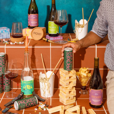 A ledge is messy with half-filled wine glasses, wine bottles, paper takeout containers and a Jenga game