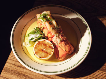 A whole baked lobster tail dressed with parsley fennel and lime juice is served over a sweet corn purée
